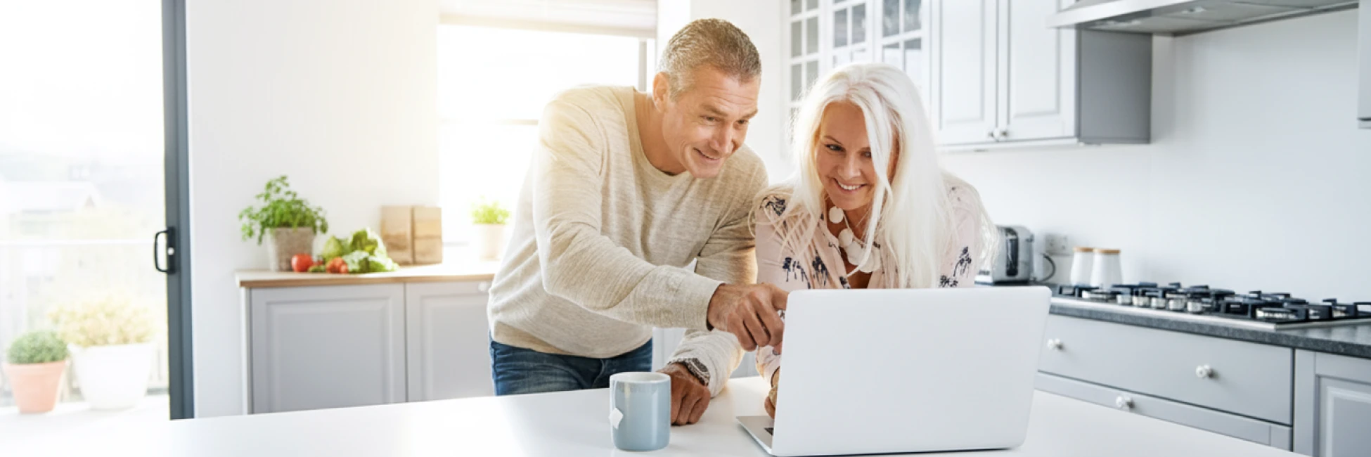 Smiling couple near retirement reviewing Social Security, Medicare, and withdrawal order online